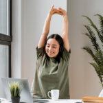 Effective Workplace Wellness Strategies for a Healthier Work Environment A woman with a headset stretching after having a video call on her laptop