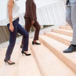 female and male coworkers participating in a corporate steps and fitness challenge walking up and down stairs